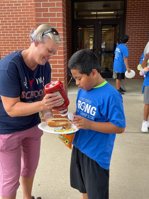 A woman and boy eating hot dogs at an event.