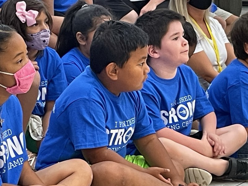 A group of children sitting in front of each other.