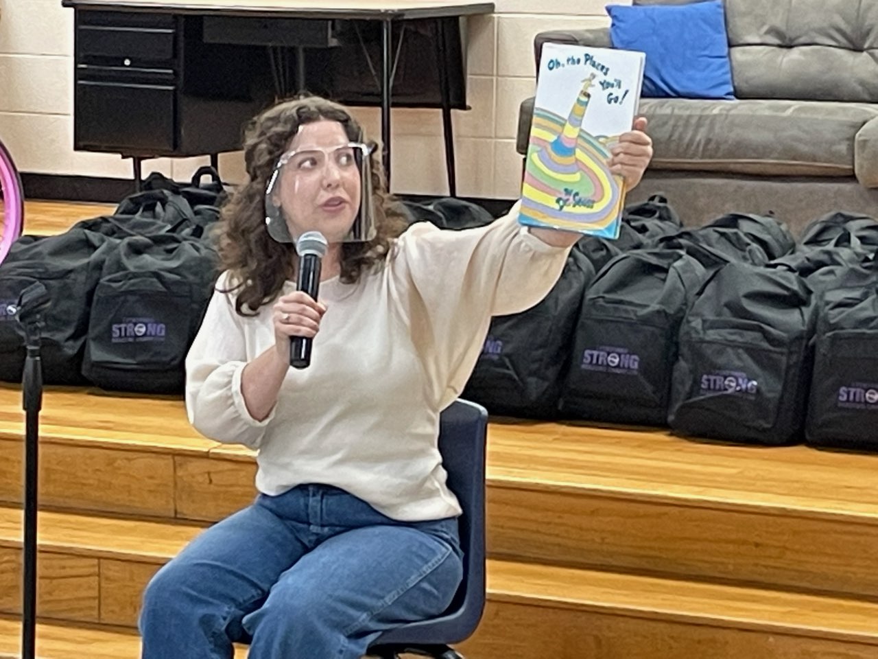 A woman sitting in front of a microphone holding up a book.