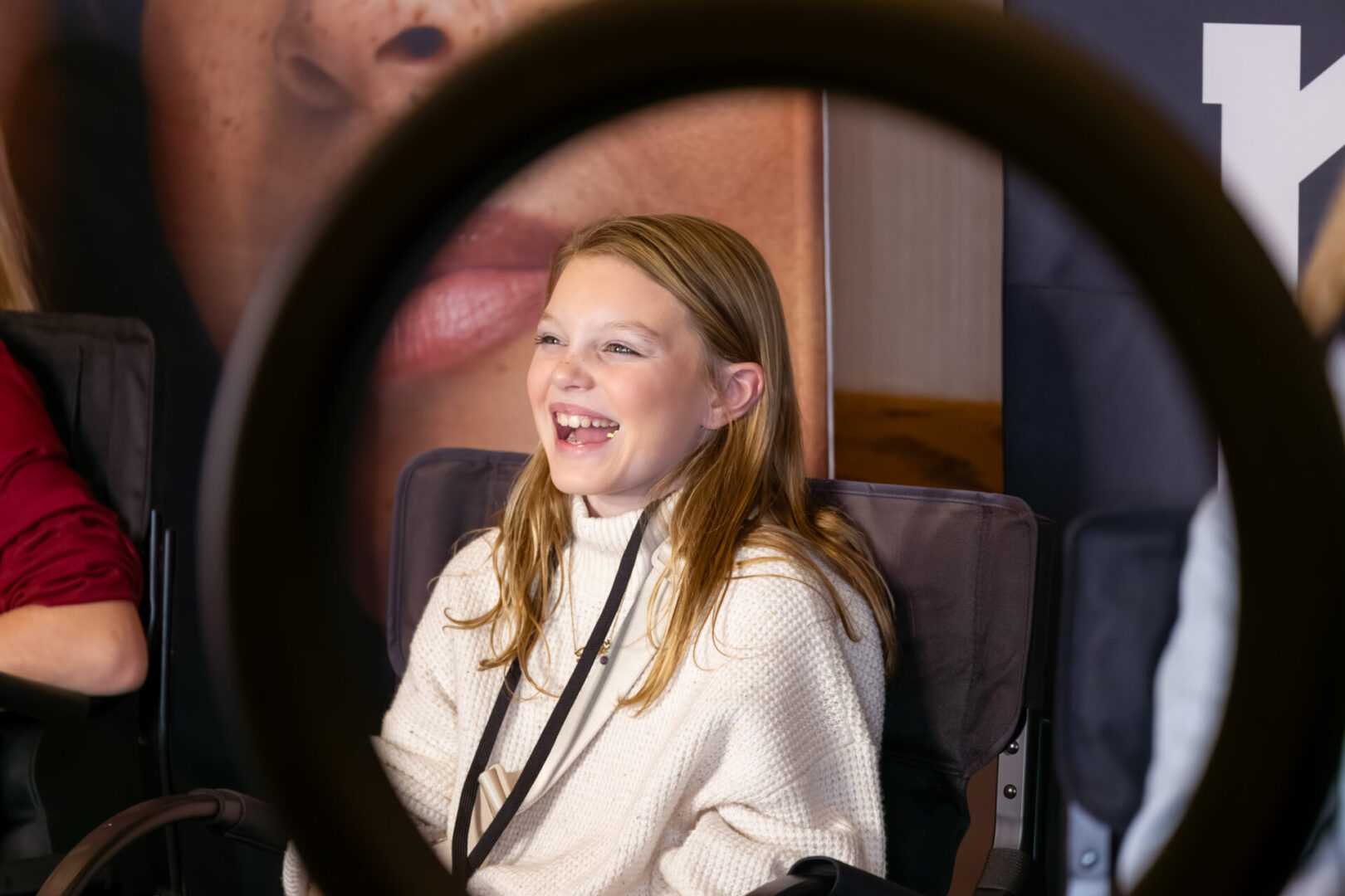 A girl is smiling through the ring of her camera.