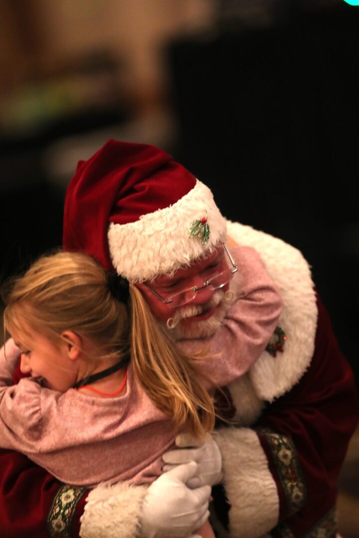 A girl is sitting on santa 's lap