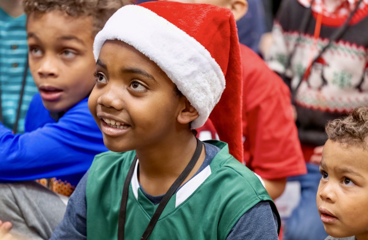 A boy wearing a santa hat and smiling.
